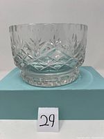 Clear crystal bowl displayed on a light blue box, showing side profile and intricate cut glass design.