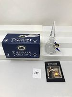 Photo of the crystal perfume bottle, blue box, and booklet laid out on a white background.