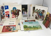 Display of multiple US mint stamp sets in original folders and envelopes arranged upright and laid out flat.