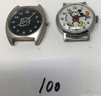 Two vintage Disney watches, one Mickey Mouse design, one black dial with logo, both missing bands, placed side by side