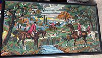 Full view of the vintage needlepoint tapestry showing the hunting scene with riders on horseback and dogs crossing a stream.