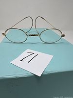 Front view of glasses on blue surface showing oval lenses and ear hooks