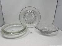 Three medium-sized glass bowls: one vintage Hughes Cornflower bowl with intricate starburst and floral patterns, plus two additional clear glass bowls with decorative rims and bases.