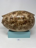 Side view of the vintage earthenware poultry roasting vessel with lid, showing the brown leaf pattern on beige background.
