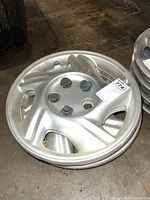 Single Pontiac 15-inch silver wheel cover showing the five lug nut design and condition with minor scuffs and wear.