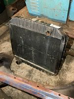 Front and side view showing the full radiator standing on the floor with visible inlet and outlet ports, radiator core, top and bottom tanks, showing the used condition.