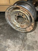 Steel rim 16x6.5 with rust from front angle showing 8 bolt holes and rust spots