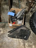Box containing various Chevrolet Equinox parts including taillights and side mirrors, mud flaps in foreground