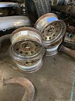 Four stacked chrome steel wheels with visible surface rust, showing bolt holes and rim edges.