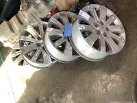 Four used 18x7 Chevrolet Equinox wheels arranged on floor showing wear, dirt, and overall condition.