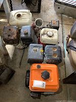 Top view showing three gas-powered engines with visible wear and damage, one orange, one black, one white tank