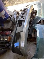 Front view of chrome bumper cover and lower spoiler laid on ground