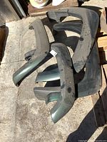 Overhead view of four used fender flares laid on concrete surface showing front and rear pairs