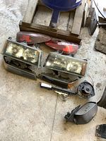 Overview of all GM Colorado parts including headlights, signal lights, tail lights, door switch panel, side mirror, and vehicle fan motor on concrete floor.
