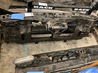 Front view of the metal radiator support showing cutouts and mounting points, surface wear visible.