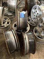 Photo showing multiple steel GM wheels, displaying rims and outer edges, showing rust and age wear