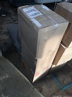 Three sealed cardboard boxes stacked on a floor, showing outer packaging for hand sanitizer bottles inside.