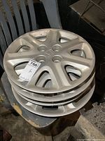 Four stacked silver Honda wheel covers showing the top cover's full face including Honda emblem and the shape of the cut-out sections.