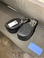 Pair of black Jeep bumper ends placed on a gray fabric car seat, showing curvature and mounting hardware.