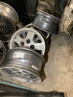 Photo showing four used mag wheels stacked and laid on a floor, highlighting surface wear and corrosion.