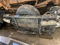 Front view of the radiator support assembly with headlights, showing wear and dust accumulation.