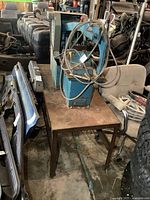 Full side view of the machine on steel table surrounded by various automotive parts, highlighting the machine's overall condition and size.
