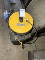 Top view of yellow and black Bayco retractable cord reel with attached beige cord missing plug.