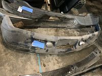 Front angle showing bumper with fog lights and mounting brackets, surface dirt and usage marks visible