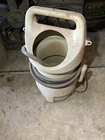 Front view of the sandblaster tank showing handle opening and coiled hose.