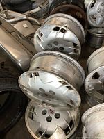 Four GM Oldsmobile wheels stacked, showing hubcaps with Oldsmobile logo and signs of wear.