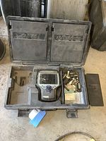 Plastic carry case open showing Genesis scan tool device and compartments with numerous adapter cards and modules.
