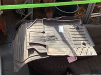 Set of three Subaru SUV floor mats stacked resting on tire. Visible surface dirt and wear but intact.