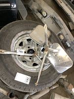 Pair of vintage stainless steel towing mirrors placed on a tire with mounting arms visible.