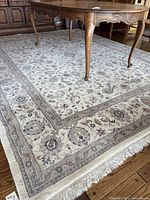 Photo showing the overall rug with furniture resting on it, highlighting the intricate border and patterns.