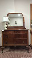 Wooden dresser with mirror front view showing three drawers and attached mirror with rounded corners and lamp on top (lamp not included).