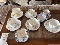 Overview of eight teacups and seven saucers on table