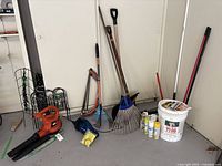 Full view of gardening and yard work tools including blower, rakes, shovel, painting supplies, and vacuum cleaner.