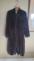 Full-length front view of dark brown mink fur coat on hanger