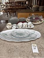 Overall view of the collection of serving dishes, plates, and bowls arranged on a countertop in a dining room setting.