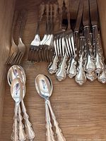 Assorted forks and knives laid out on wooden surface