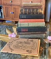 Stack of 11 antique books on glass table showing varying cover colors and wear.