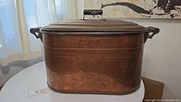 Front side view of the antique copper boiler wash tub with visible embossing 'ATLANTIC' on side and two side handles.