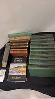 Overview of antique books including a green-bound series and other vintage books with varied spine colors, plus a paperback novel.