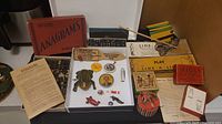Overview of antique toys and games collection showing various games boxes, letter tiles, a tin frog toy, and small collectible items.