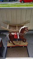 Photo showing the full toy rocking horse mounted on the wheeled cart base outdoors.