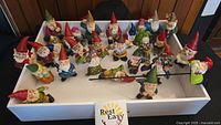 Overview photo showing 23 gnome figurines of different sizes and styles placed on a white surface.