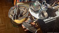 Overview of multiple silver plated platters, pitchers, and the assay tray on a table, with natural light showing surface tarnishing and wear