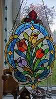 Full view of the stained glass panel with tulip design hung in a window with hanging glass beads visible on the side