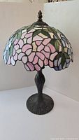 Front view of Tiffany-style table lamp showing pink flower pattern, green leaves, and metal base.