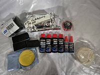 Photo showing Evercoat Triple Gloss compound bottles, polishing cloths, black sponge-like blocks, backing pad, and other items.